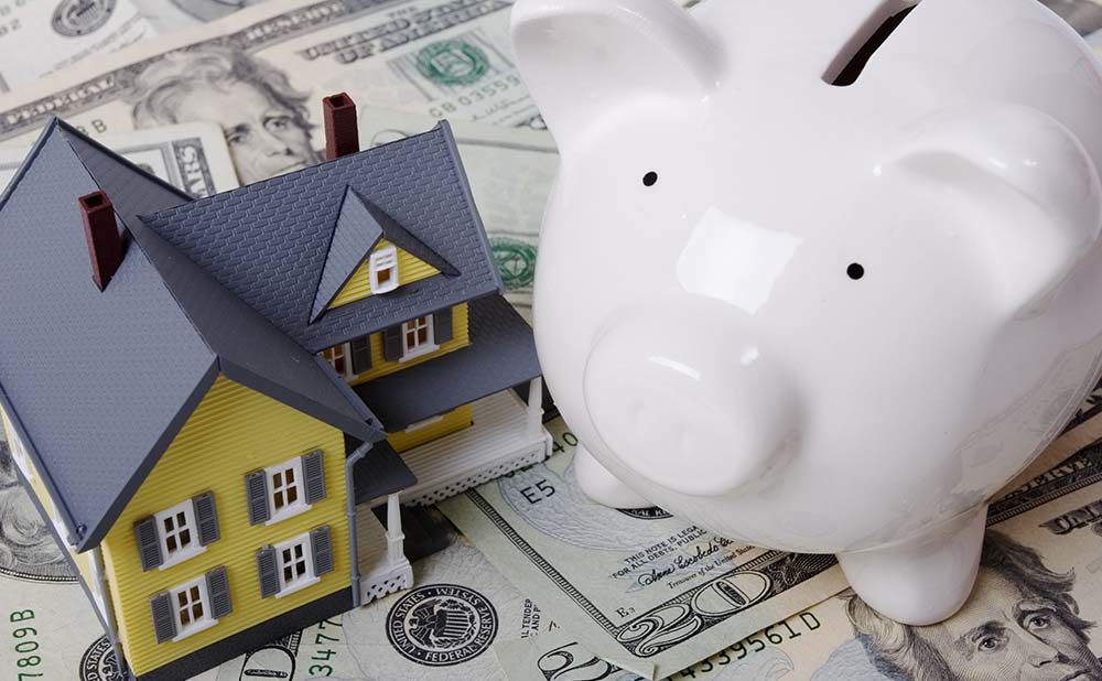 Home and Piggy Bank On Top of Home Down Payment Money